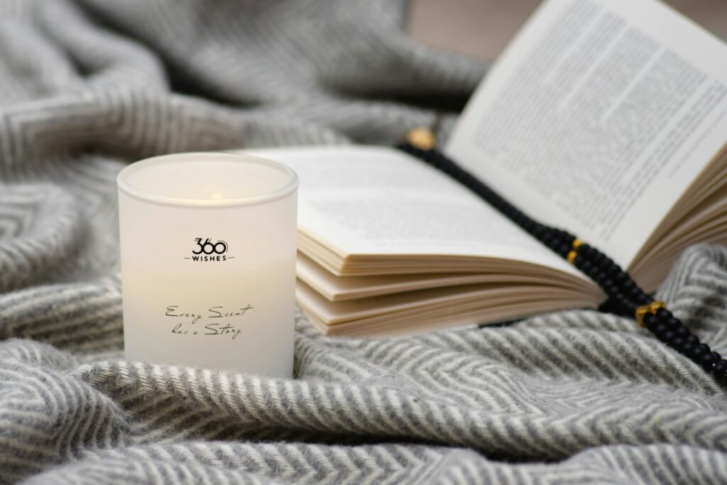 9 Best Scented Candles for Diwali 2026: Premium Gifts and Decor White scented candle beside an open book on a knit blanket