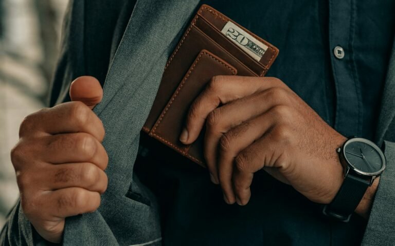 Man holding a leather wallet and wearing a watch