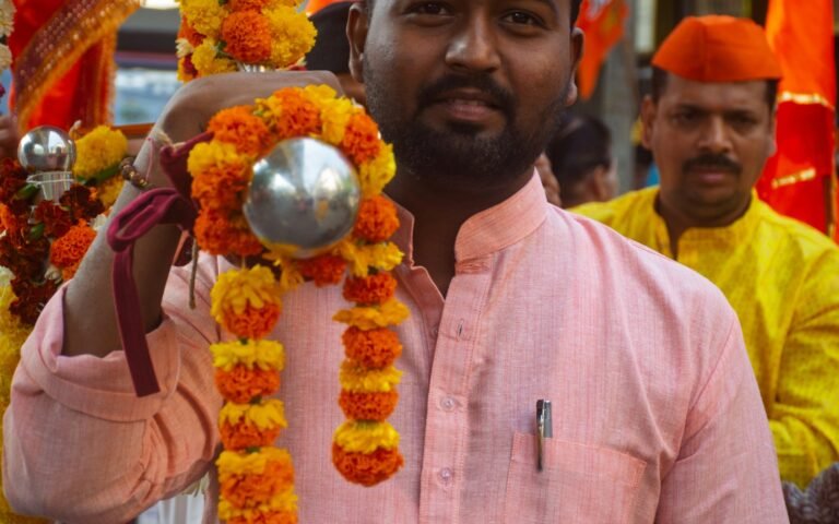 Man in a festive pink kurta carrying a floral garland