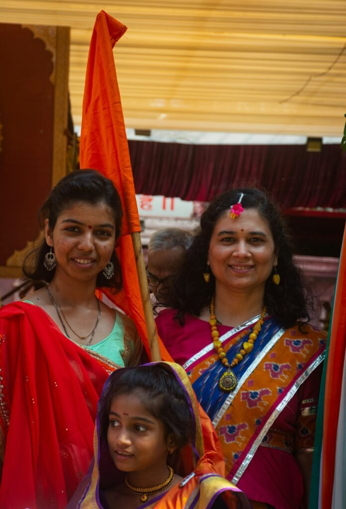 Diwali Outfits for the Whole Family Under ₹5,000 (2026) Two women and a girl in bright traditional outfits at a festival