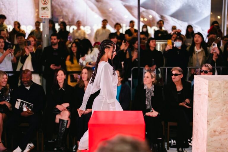 A model walks a fashion show runway as the audience watches