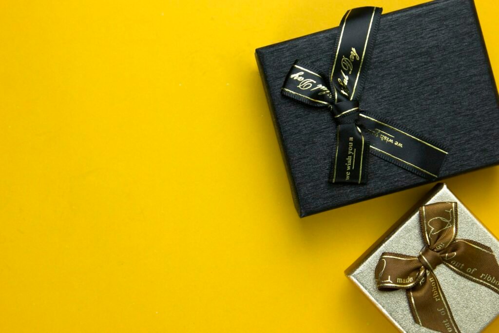 Black luxury gift box with a gold ribbon on a bright yellow background