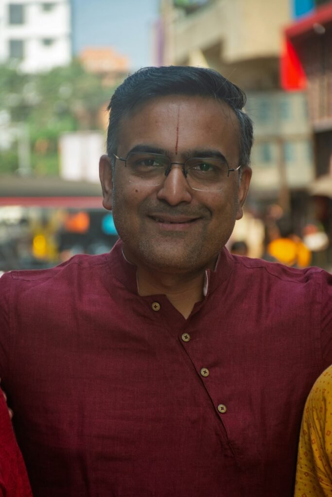 8 Best Diwali Kurtas for Men Under ₹1,000 (2026) Smiling man in a maroon kurta at a festive gathering