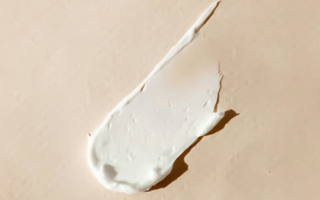 Smear of white moisturising cream on a beige surface