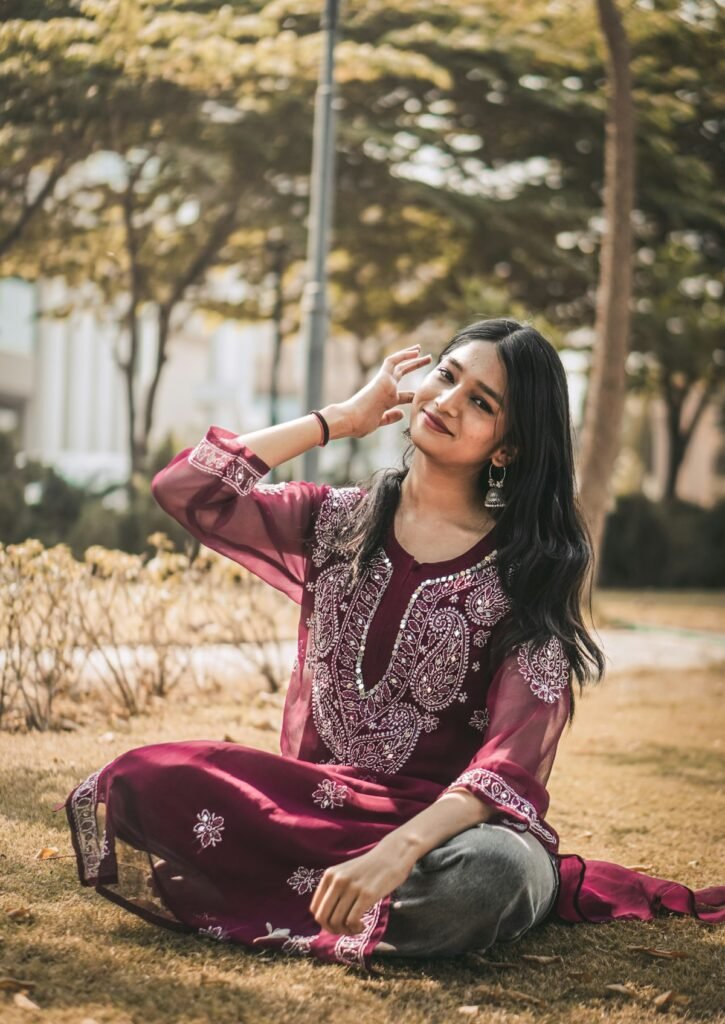 Woman in a maroon chikankari kurta set sitting outdoors